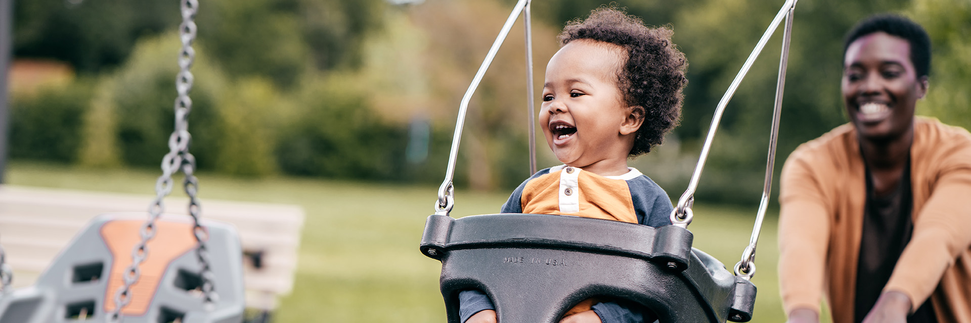 Mom pushing child on swing