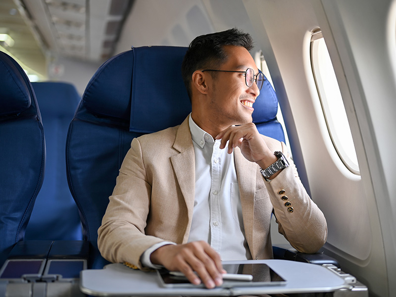 Traveler Sitting in Airplane Seat with Tablet on Tray Table