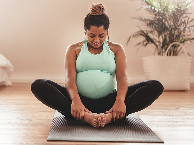 Pregnant woman doing yoga on floor