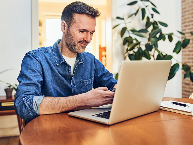 man searching spine doctor near me on laptop and phone