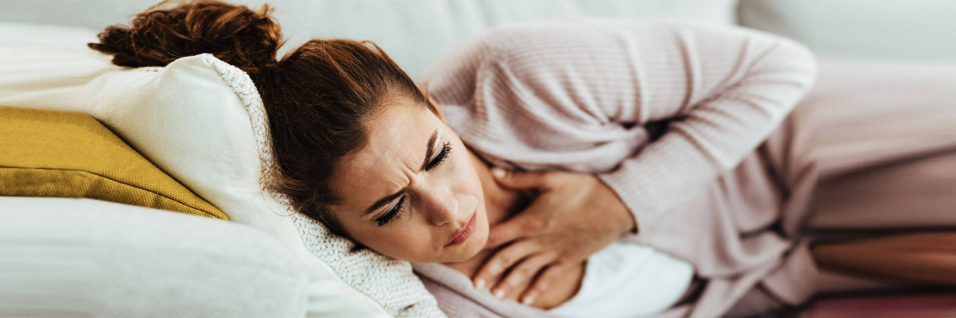 Woman on couch touching throat
