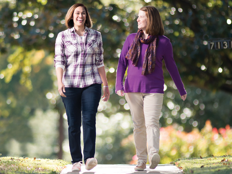 Two people walking together on a neighborhood sidewalk